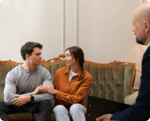 A man and woman sitting on a couch receiving divorce counseling.
