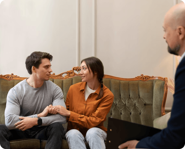 A man and woman sitting on a couch receiving divorce counseling.