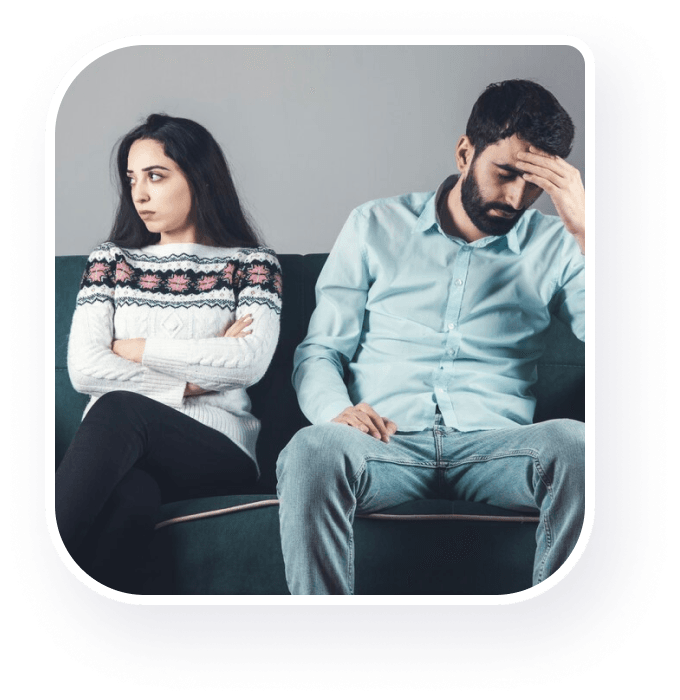 A couple seeking therapy seated on a couch displaying distress.