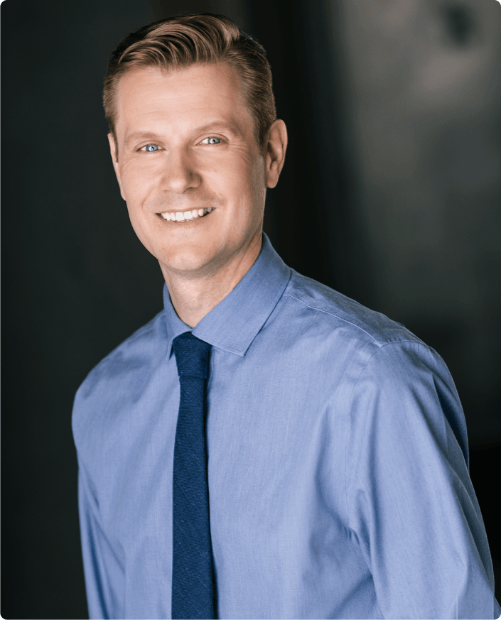 Jordan Penner, a smiling man in a blue shirt and tie.
