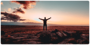 A man embracing mental health while standing on top of a rock with his arms outstretched.