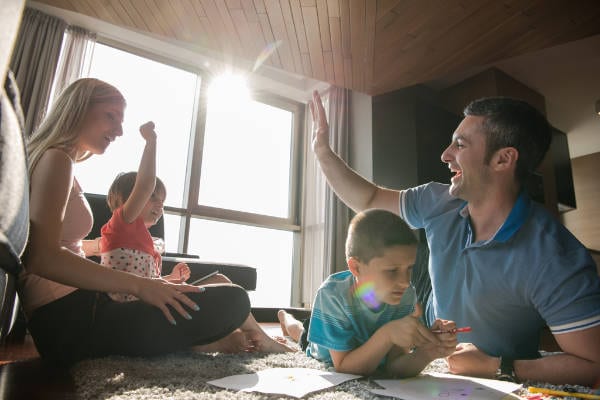 A family is engaging in playtime with their children in the living room.