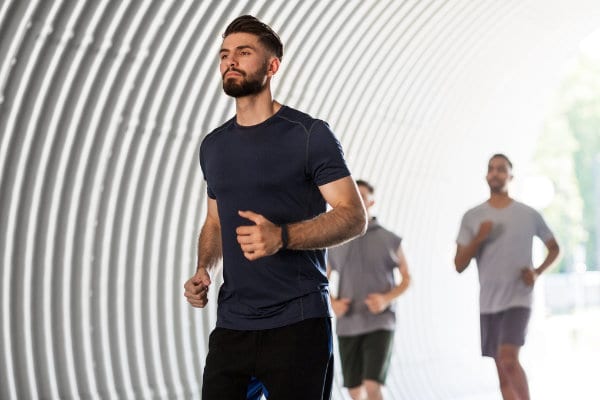 A group of men improving their mental health by jogging in a tunnel.