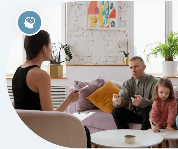 A family sitting in a living room with a child playing a video game.