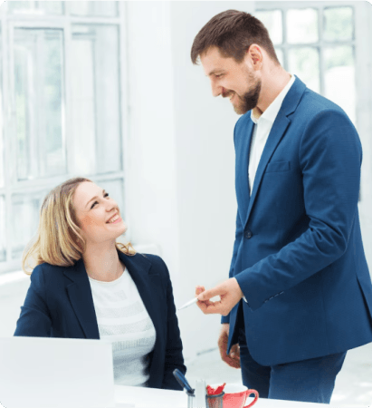 A man and a woman promoting mental health by smiling at each other in an office.