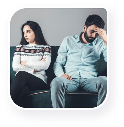 A couple seeking therapy seated on a couch displaying distress.