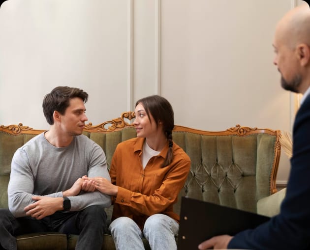 A man and woman sitting on a couch receiving divorce counseling.