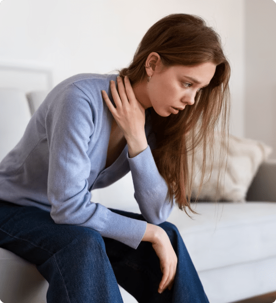 A woman displaying signs of discomfort on a couch, indicating potential mental health issues.