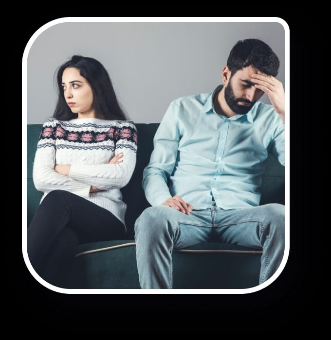 A couple seeking therapy seated on a couch displaying distress.