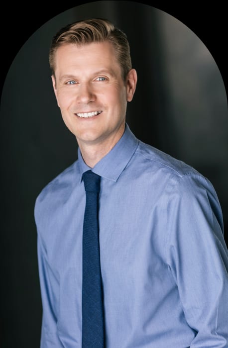 A smiling clinical counselor in a blue shirt and tie.