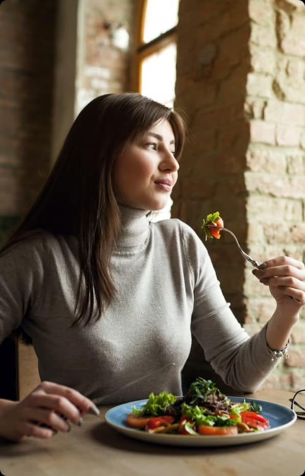A woman practicing self-care by consuming a nutritious salad.