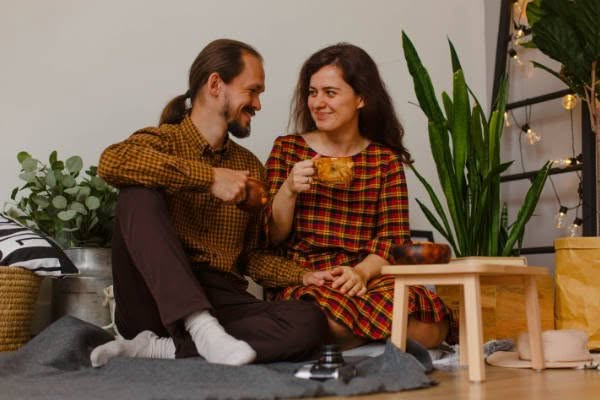 Young couple participating in Couples Therapy while sitting on the floor and drinking tea.