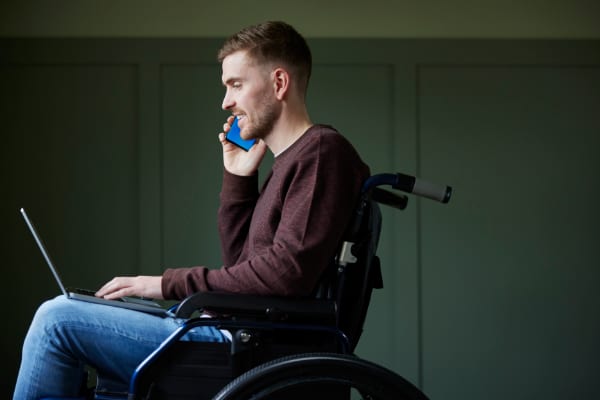 A man in a wheelchair using a phone to discuss mental health.